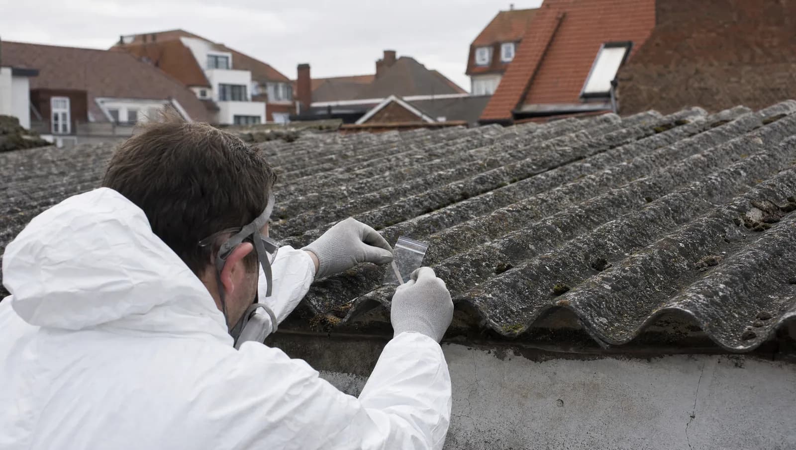 Ouder appartementsgebouw aan de Belgische kust met een asbestdeskundige die een dak inspecteert